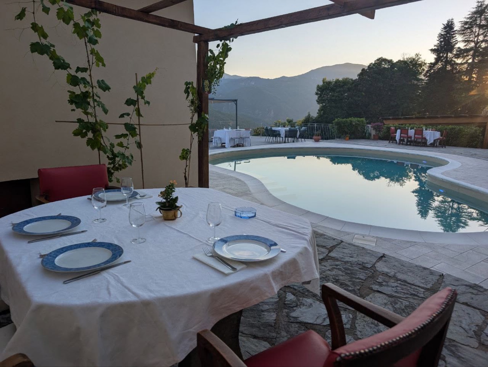 Tavola apparecchiata sotto il pergolato con vista piscina
